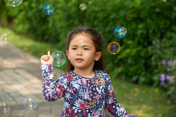 Curious little girl looking at soap bubbles - 写真・画像