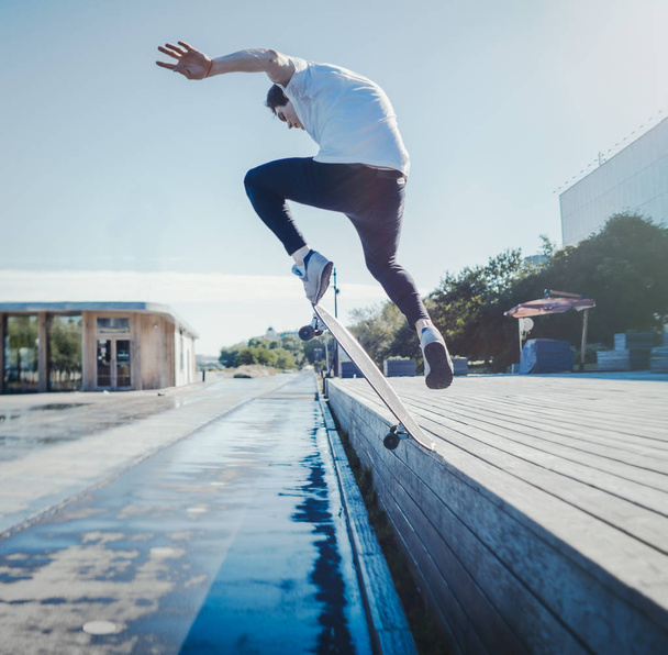 Young attractive man riding and jumping longboard in the park. - Photo, Image