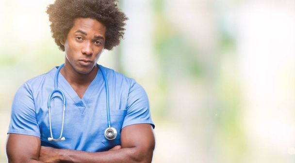 Médico cirurgião afro-americano homem sobre fundo isolado cético e nervoso, desaprovando a expressão no rosto com os braços cruzados. Pessoa negativa
. - Foto, Imagem
