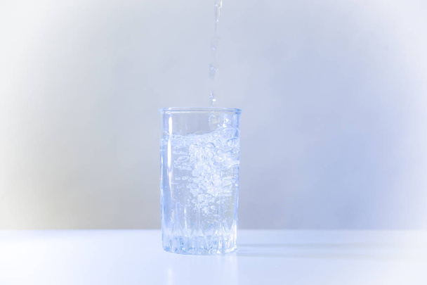 Copo de água pura em uma mesa de cozinha branca
 - Foto, Imagem