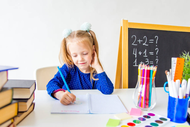 Happy cute industrious child is sitting at a desk indoors - 写真・画像