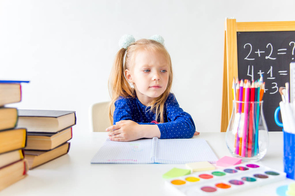 Happy cute industrious child is sitting at a desk indoors - Foto, Bild