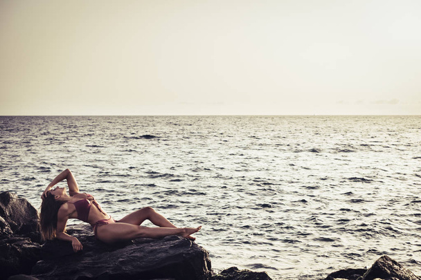Nuori nainen nauttii ja poseeraa meren rannalla kesäloman aikana
 - Valokuva, kuva
