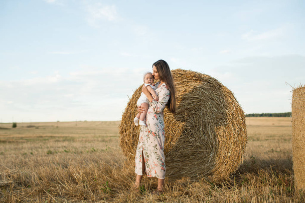 Mom and daughter in a field with stacks - Foto, imagen