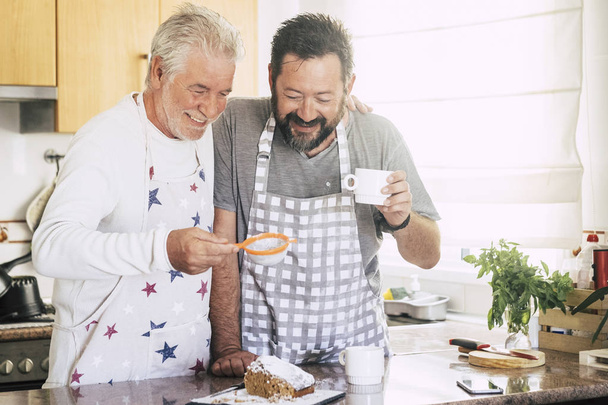 Vater und Sohn backen zu Hause in der Küche gemeinsam Kuchen - Foto, Bild