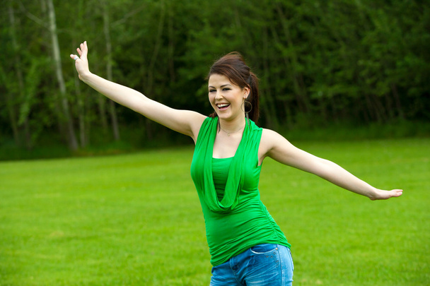 leuk meisje met open armen in groene veld. - Foto, afbeelding