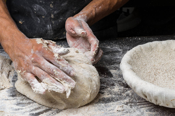 Manos masculinas amasando masa en espolvoreado con mesa de harina, primer plano
 - Foto, Imagen