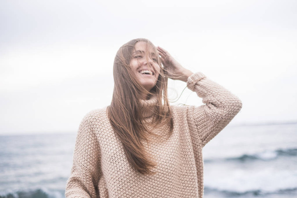 portrait of young woman in sweater posing on ocean background - Zdjęcie, obraz