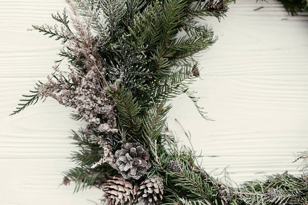 Corona de Navidad. elegante corona de Navidad rústica en la puerta de madera blanca con conos de pino, ramas de abeto, nieve. espacio para el texto. decoración hecha a mano para las vacaciones de invierno
. - Foto, Imagen