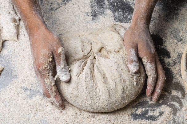 Mains masculines pétrissant la pâte sur saupoudré de table de farine, gros plan
 - Photo, image