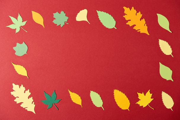 frame made of colorful papercrafted leaves arrangement on red background - Φωτογραφία, εικόνα