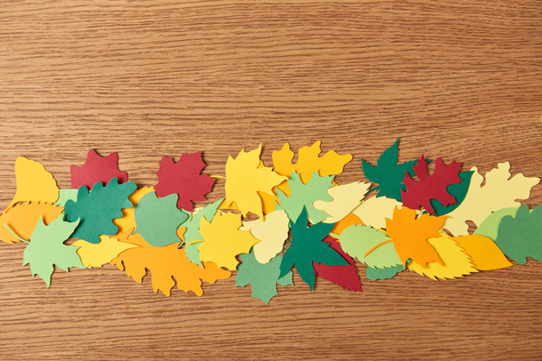 top view of colorful papercrafted foliage arrangement on wooden background - Fotografie, Obrázek