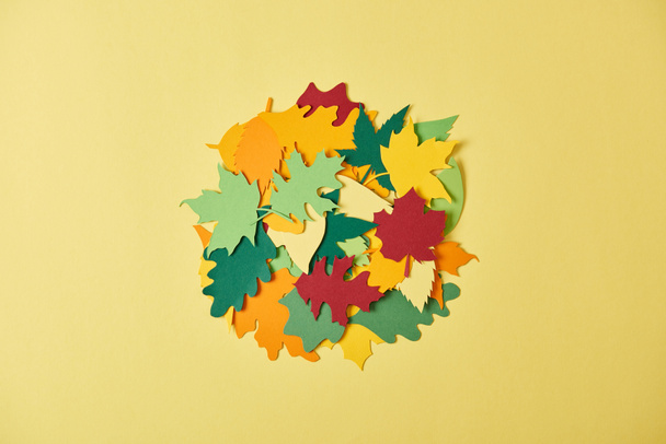flat lay with colorful papercrafted foliage arranged in circle on yellow background - Foto, Bild
