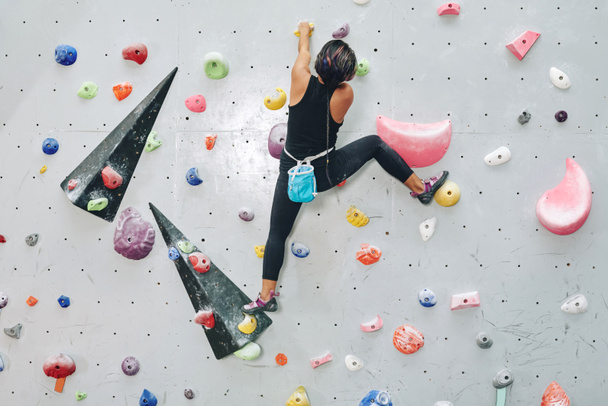 Back view of woman on climbing wall  - 写真・画像