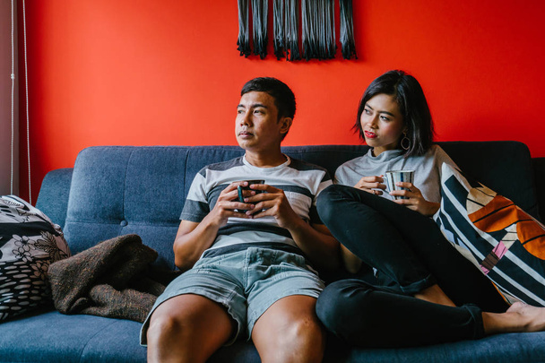 married Malay couple sit on their couch in a trendy and modern living room together - Photo, Image