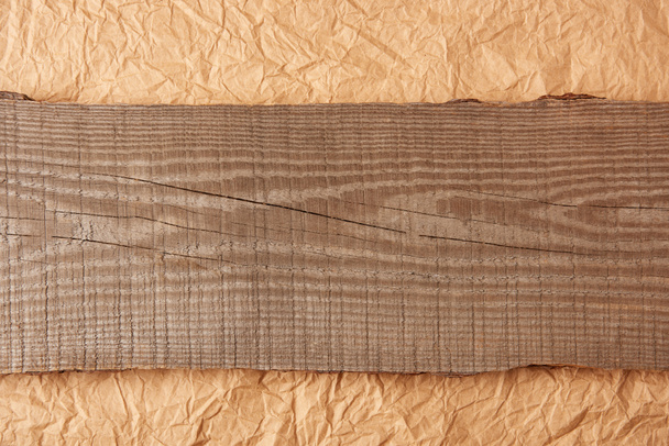 top view of wooden plank on crumpled paper backdrop - Photo, Image