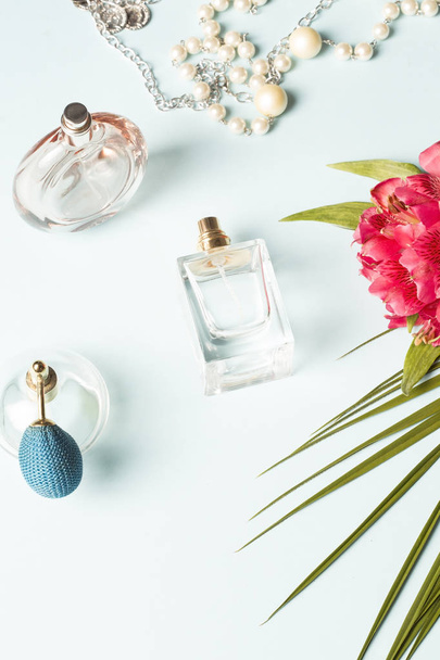 Perfume bottles, beads and the wild orchid with the palm leaf - Фото, изображение