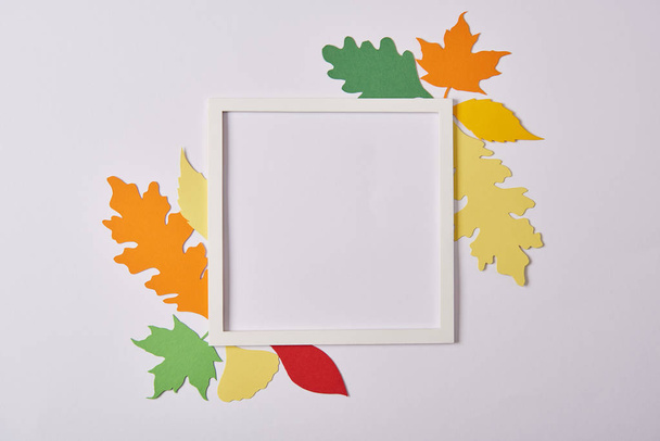 El yapımı kağıt yaprakları ve beyaz masa üzerinde boş çerçeve ile düz lay - Fotoğraf, Görsel