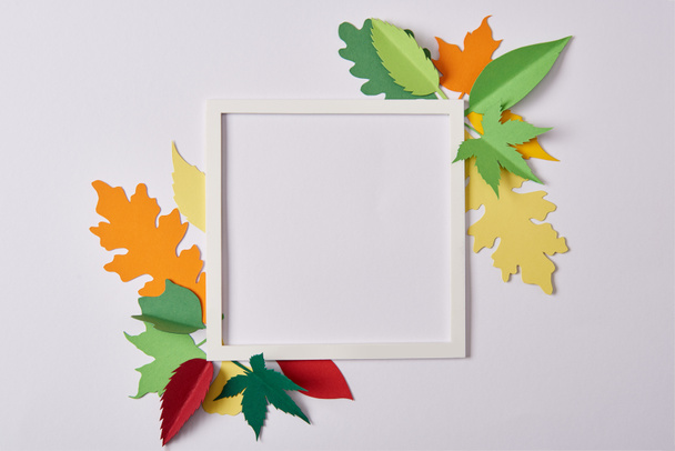 vlakke leggen met handgemaakte papieren bladeren en leeg frame op wit tafelblad - Foto, afbeelding
