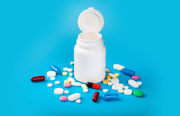 Medicamentos, suplementos e drogas em uma garrafa no fundo azul
 - Foto, Imagem