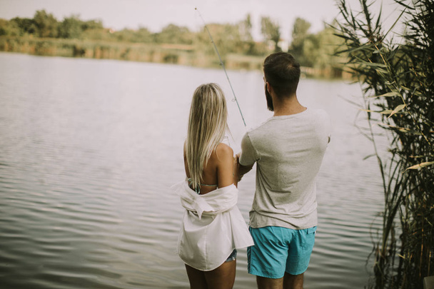 Charmant jeune couple pêchant ensemble au bord d'un lac le jour d'été
 - Photo, image