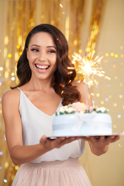 Веселая возбужденная красивая молодая женщина с волнистыми волосами, держа торт на день рождения
  - Фото, изображение