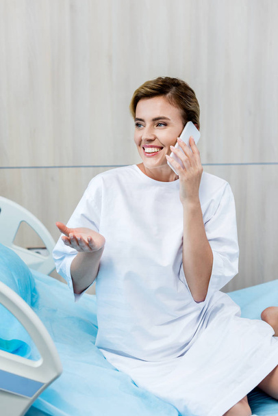 счастливая пациентка жестикулирует вручную и разговаривает на смартфоне в больничной палате
 - Фото, изображение