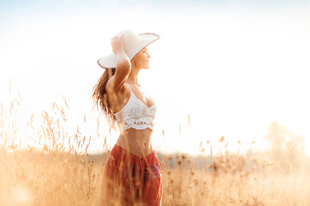 Молодая улыбающаяся привлекательная девушка в поле на закате. Открытая романтическая концепция
 - Фото, изображение
