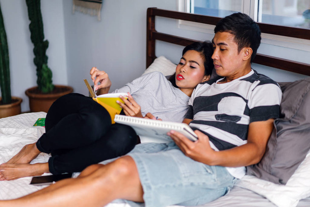 Portrait of a young and attractive Malay Asian couple sitting around lazily in bed on the weekend.  - Valokuva, kuva