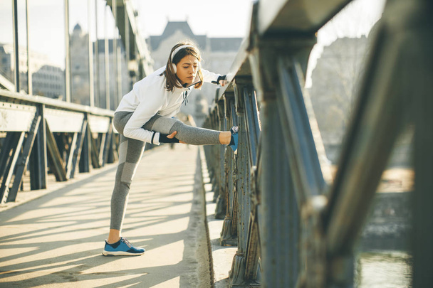 Young sportswoman stretching and preparing to run outdoor - Valokuva, kuva