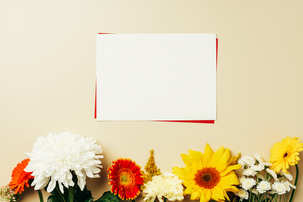 επίπεδη lay με κόκκινες και άσπρες κενές κάρτες και διάφορα λουλούδια σε μπεζ φόντο - Φωτογραφία, εικόνα