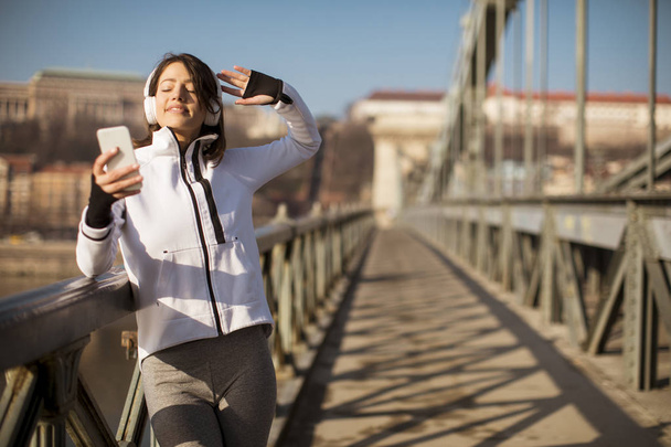 Mujer atleta joven con teléfono móvil en el bridhe en Budapest, Hungría
 - Foto, imagen