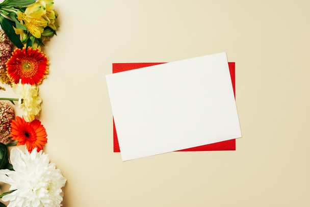 επίπεδη lay με κόκκινες και άσπρες κενές κάρτες και διάφορα όμορφα λουλούδια σε μπεζ φόντο - Φωτογραφία, εικόνα