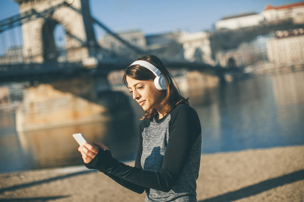 Kobieta młody sportowiec z telefonu komórkowego na bridhe w Budapeszcie, Węgry - Zdjęcie, obraz