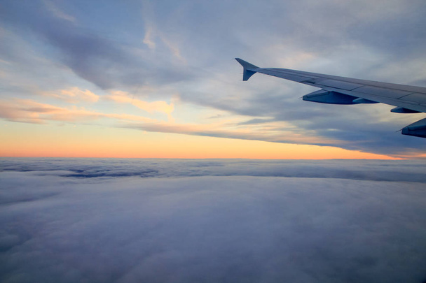 Pôr-do-sol de alta altitude sobre as nuvens de uma janela de avião
 - Foto, Imagem