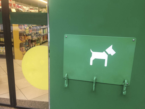 Baía de estacionamento para cães de estimação ao lado da porta do supermercado. Três mosquetões livres
 - Foto, Imagem