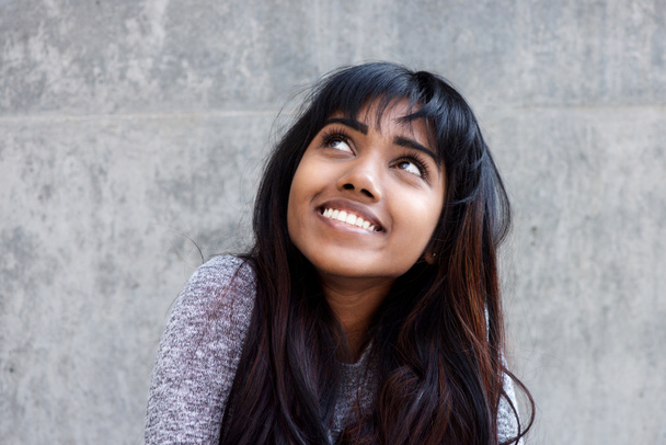 Nahaufnahme Porträt einer jungen indischen Frau, die lächelt und nach oben blickt - Foto, Bild