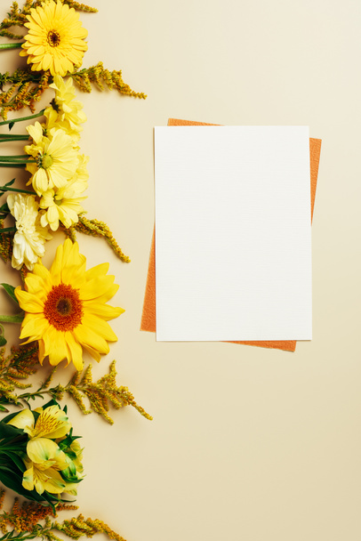 flat lay with bright flowers, empty white and orange cards on beige background - Foto, afbeelding