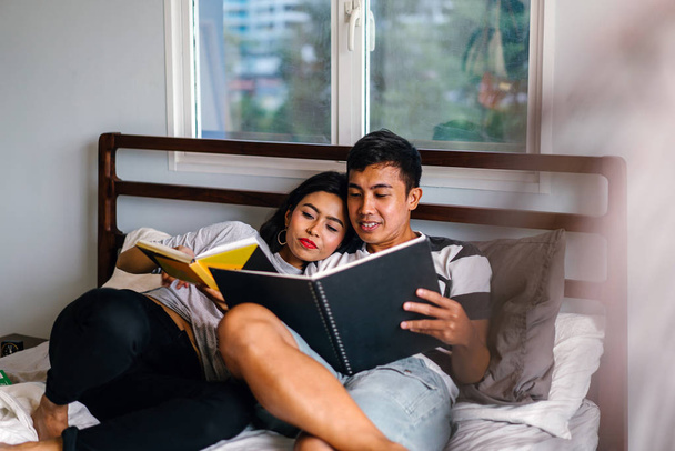 Portrait of a young and attractive Malay Asian couple sitting around lazily in bed on the weekend.  - Foto, imagen