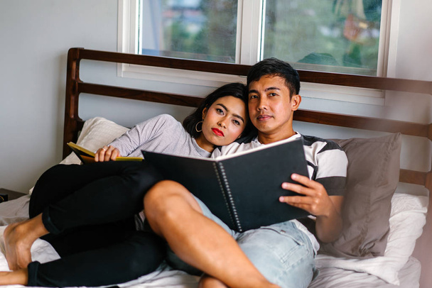 Portrait of a young and attractive Malay Asian couple sitting around lazily in bed on the weekend.  - Foto, immagini