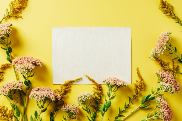 flat lay with beautiful wildflowers and blank card arranged on yellow backdrop - Foto, Imagen