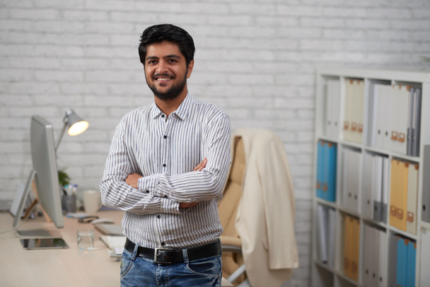 Веселий впевнено індійський бізнесмен, стоячи з руки пересічена в офісі  - Фото, зображення