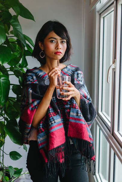 Portrait of a young, attractive and photogenic Singaporean Malay woman standing by the window in her home - Foto, immagini