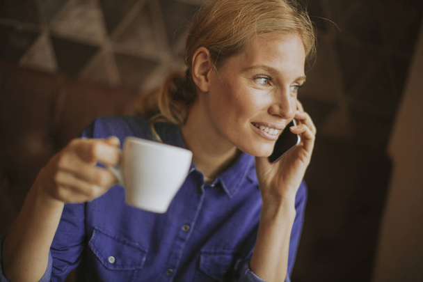 Mulher loira muito jovem com telefone celular no café
 - Foto, Imagem