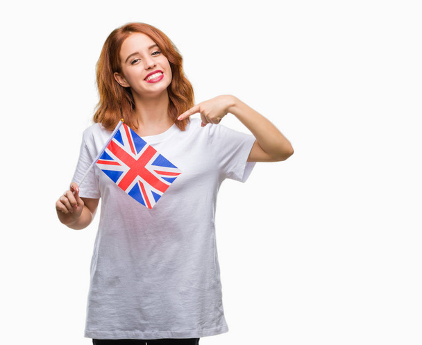 若くてきれいな女性の手と指で指している非常に幸せの分離の背景の上イギリスの旗を保持しています。 - 写真・画像