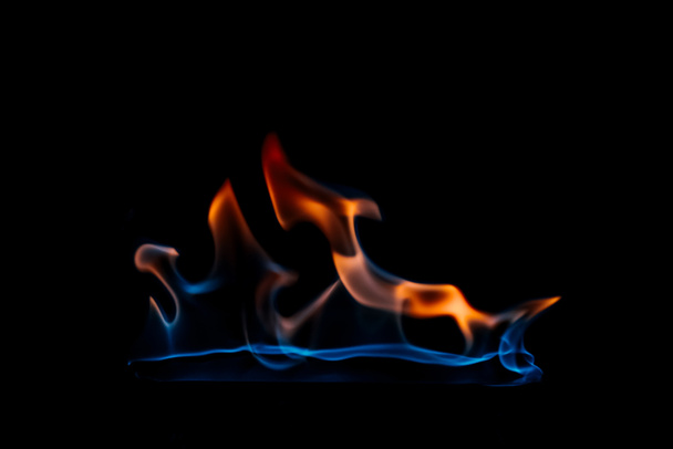 close up view of burning orange and blue flame on black background - Foto, afbeelding