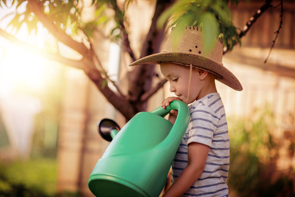 Retrato de niño pequeño al aire libre.Lindo niño regando hierba en el patio trasero
. - Foto, Imagen