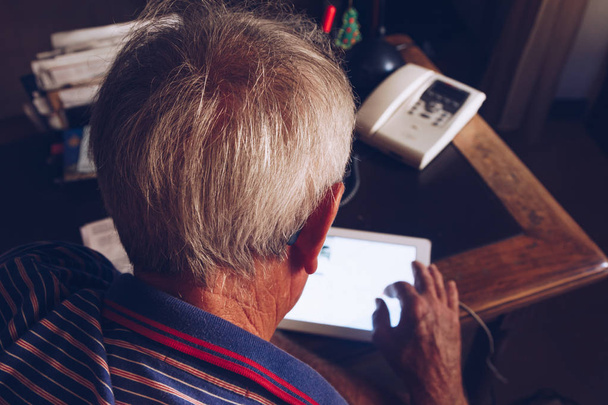 vista trasera de un hombre mayor que utiliza la tableta en la oficina de los años 70 80 - dispositivo moderno
 - Foto, Imagen