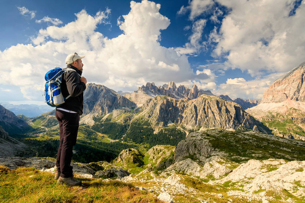 Niché dans le magnifique paysage alpin, un homme admire le paysage de haute altitude avec des sommets de montagne et un ciel nuageux
. - Photo, image