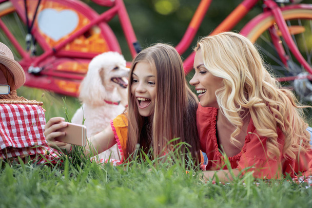 Beautiful mother and little daughter having fun together in summer park. - Zdjęcie, obraz